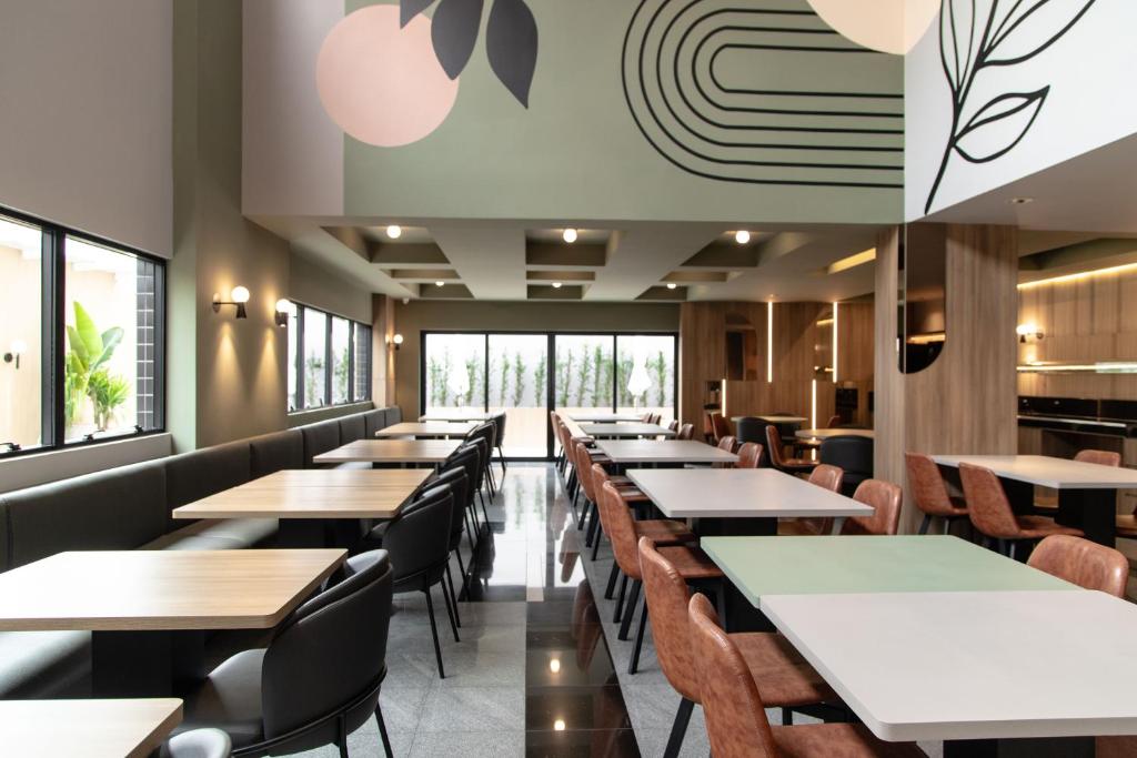 a restaurant with tables and chairs and windows at Slim Curitiba Alto da XV in Curitiba