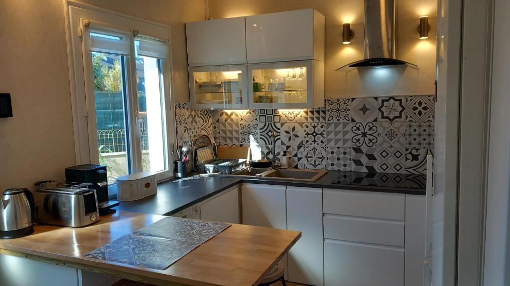 une cuisine avec des armoires blanches et un comptoir dans l'établissement Charmante Maison avec jardin entre Deauville et Honfleur, à Saint-Gatien-des-Bois