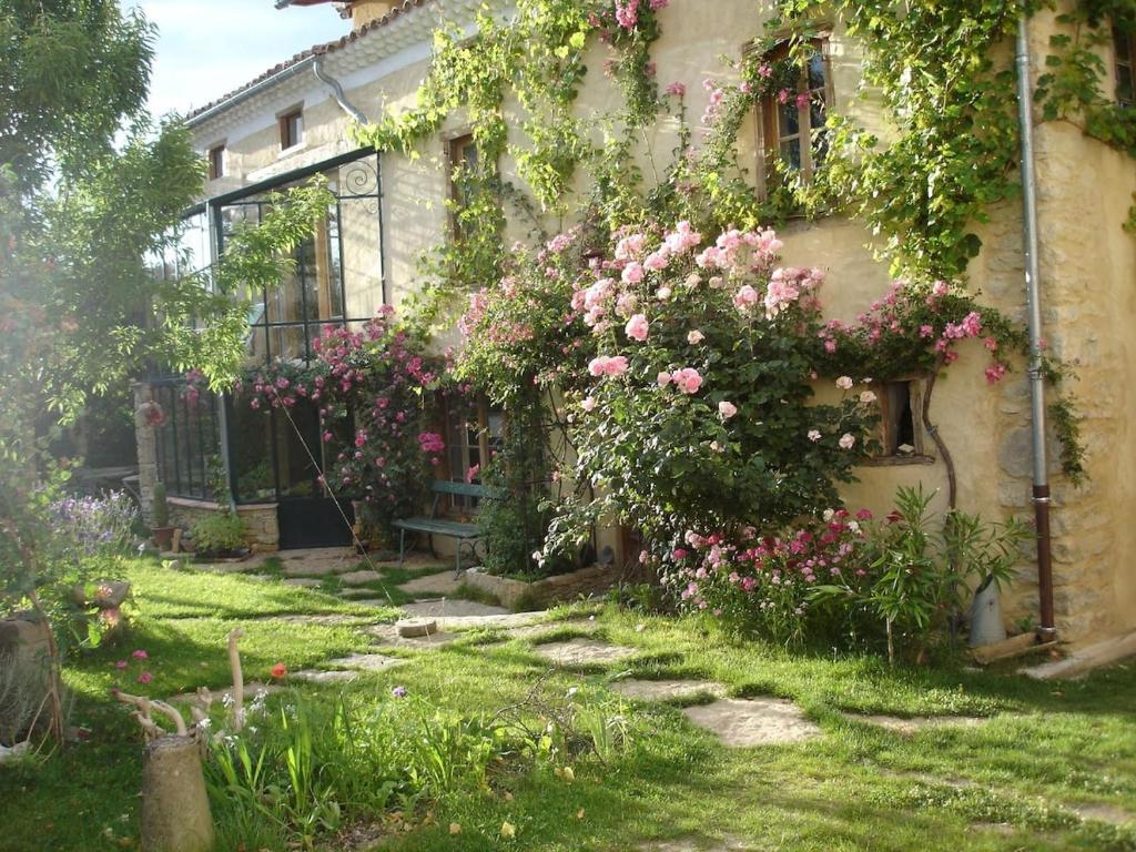 un jardin avec des roses sur le côté d'un bâtiment dans l'établissement L'abeille verte, à La Celle-sous-Gouzon
