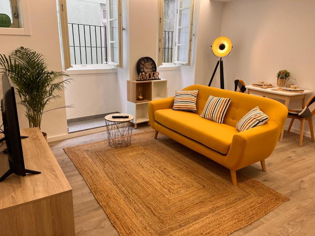 a living room with a yellow couch and a table at Valma GuestHouse in Viana do Castelo