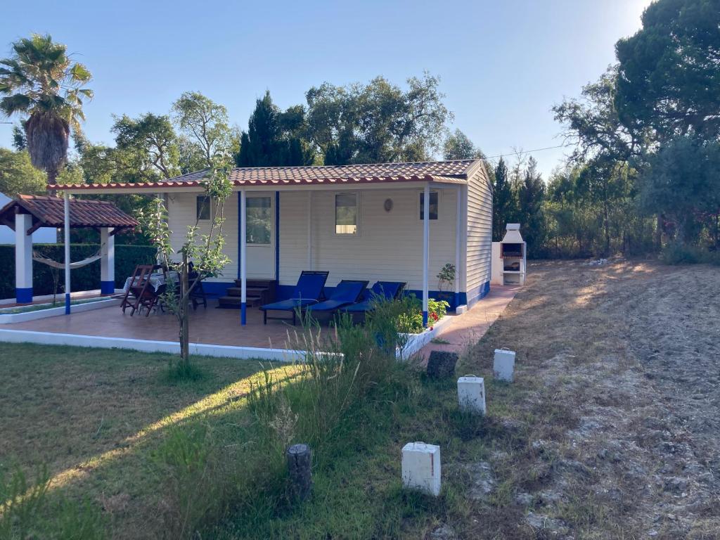 a small house with blue chairs in a yard at Casa no Monte Ninho das Perdizes perto Cercal do Alentejo in Vale de Água