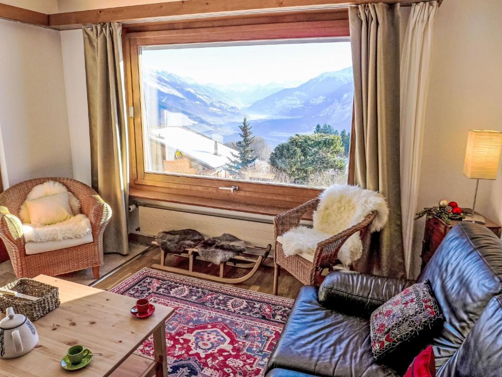 Una sala de estar con un gran ventanal con vistas. en Chalet Chalet Aglaia by Interhome, en Bluche