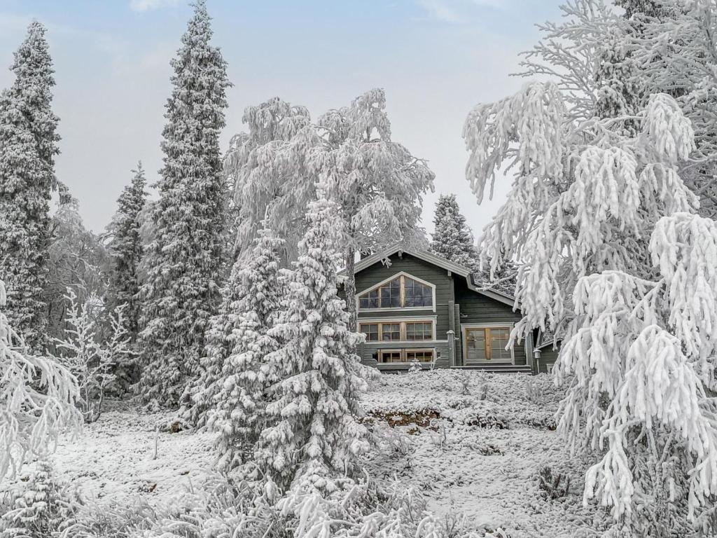 ein Haus in einem verschneiten Wald mit schneebedeckten Bäumen in der Unterkunft Holiday Home Rukaniemen kontio by Interhome in Ruka