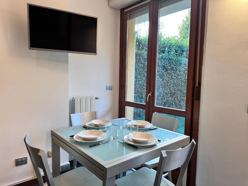a dining room with a table with chairs and a television at Monolocale con giardino privato e cucina completa in Bergamo