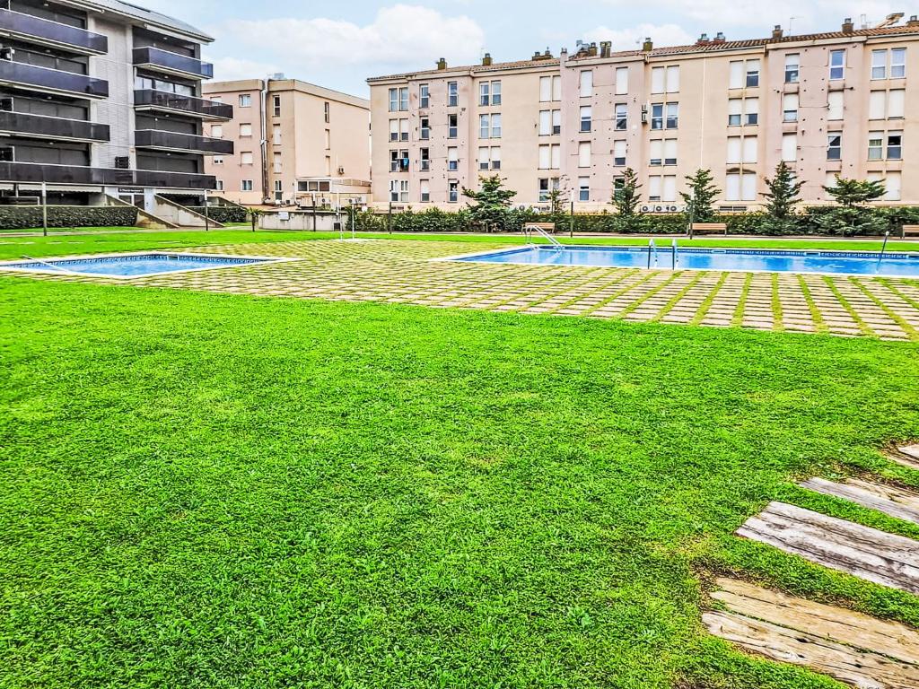 a grassy area with a building and a swimming pool at Apartment Puig Sapera by Interhome in Sant Antoni de Calonge