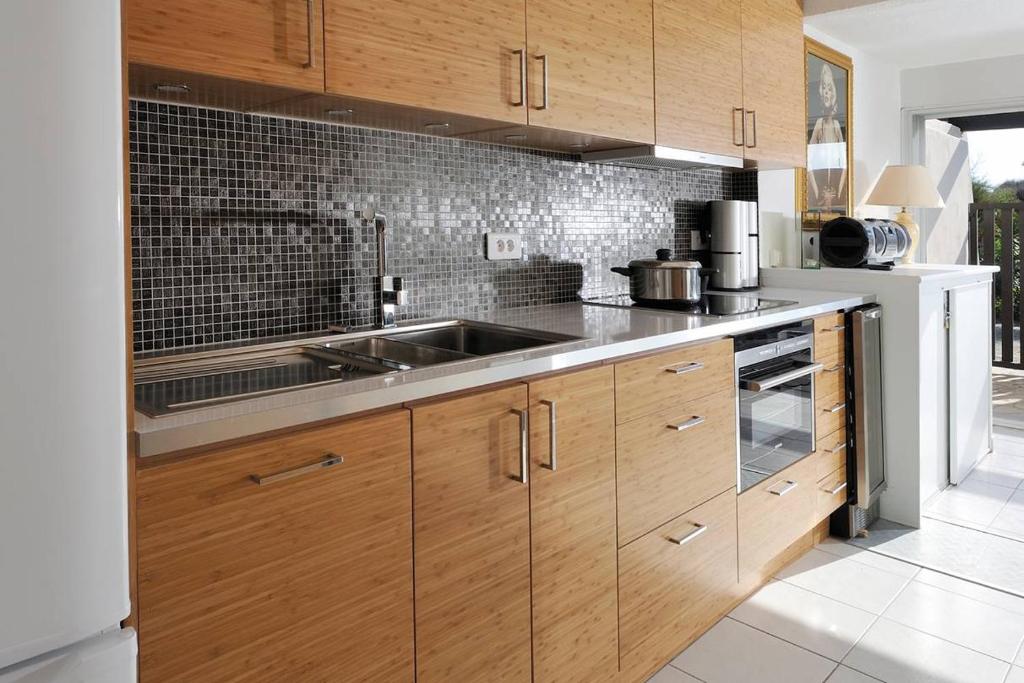 une cuisine avec des armoires en bois et un évier dans l'établissement Villa Port Nature 11 MARILYN - Luxe - 4 personnes, au Cap d'Agde