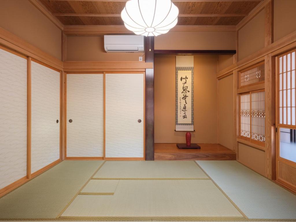 an empty room with a chandelier and windows at 薬医門の宿 in Katori