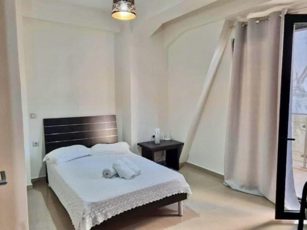 a bedroom with a bed with white sheets and a window at Dimi Studio Image in Ierápetra