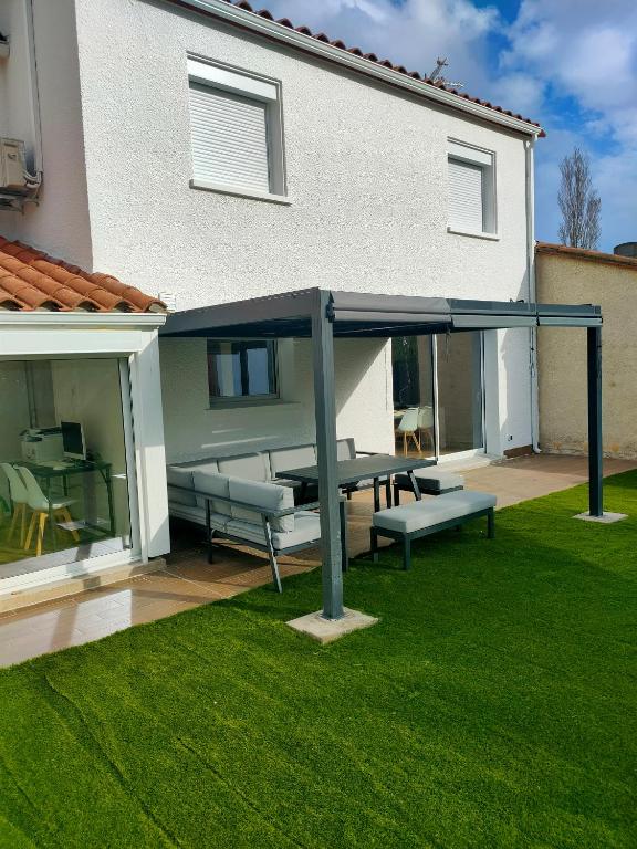 - une terrasse avec une table de pique-nique et des bancs dans la cour dans l'établissement House with 5 bedrooms and HOT TUB, à Saint Cyprien Plage