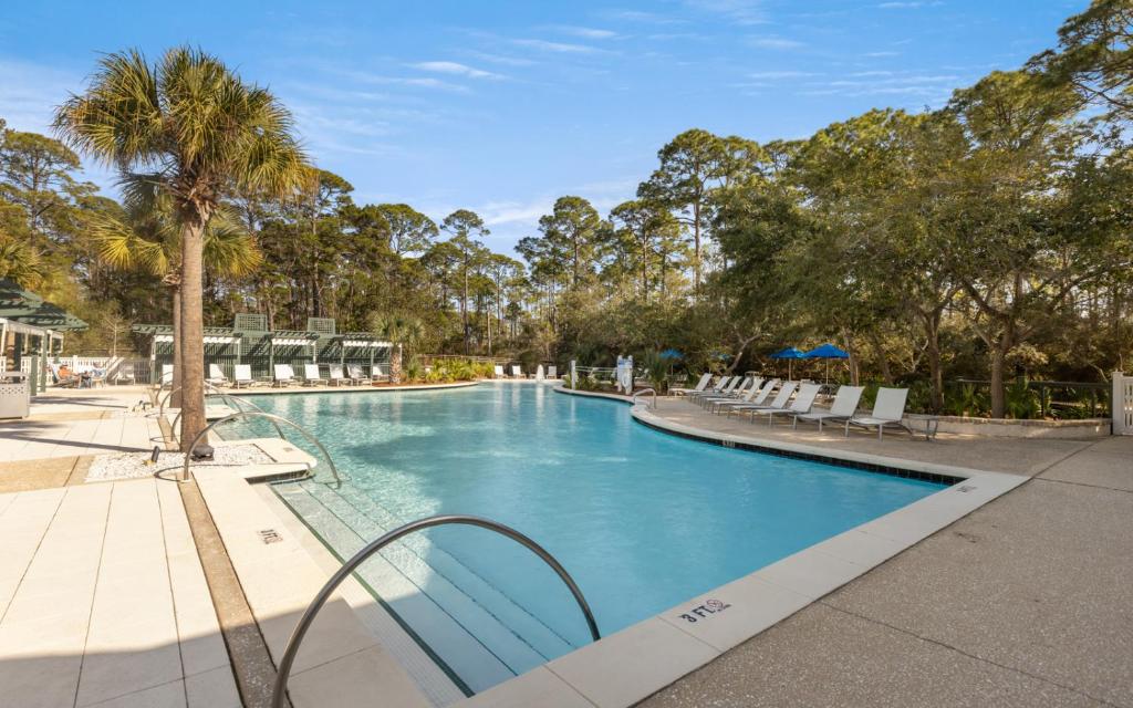 een zwembad met stoelen en een palmboom bij Our Tree House by Oversee 30A in Inlet Beach