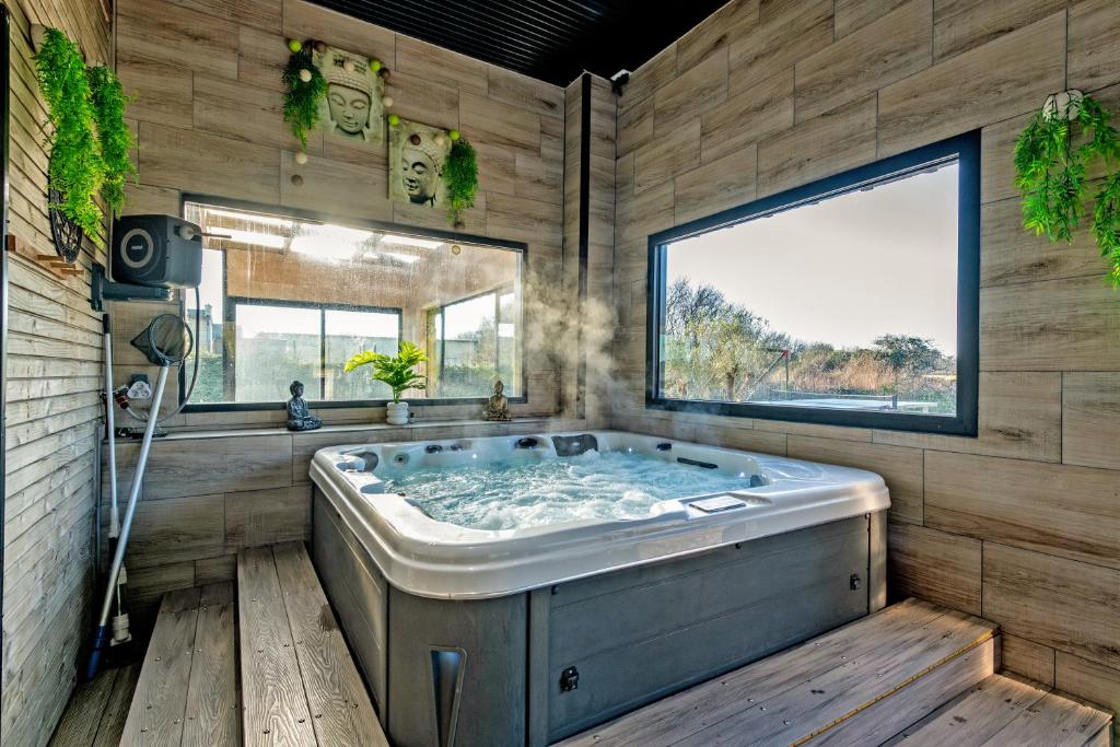 une grande baignoire dans une pièce avec une fenêtre dans l'établissement La Villa Chantalain, à Kerlouan