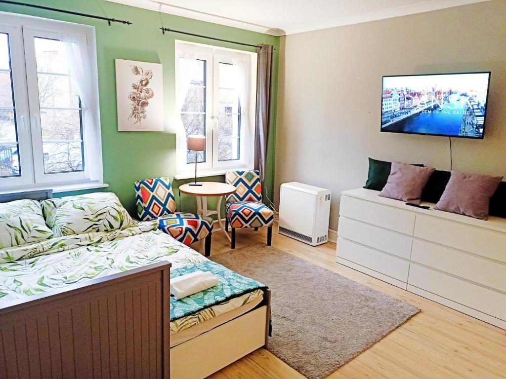 a bedroom with a bed and a tv on the wall at Brick Lane Apartment in Gdańsk
