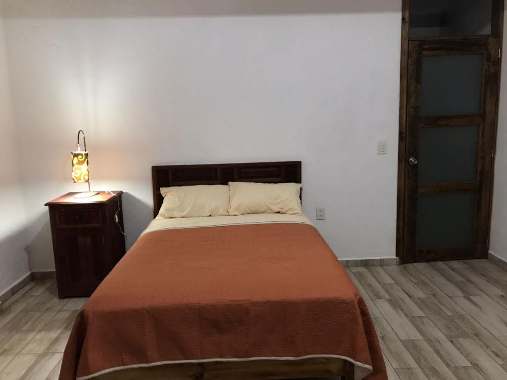 a bedroom with a bed and a night stand and a door at MI CASA EN TEPOZTLAn in Tepoztlán