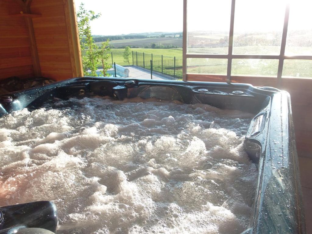a hot tub filled with water next to a window at Roulotte & Accès SPA Privatif in Pauilhac