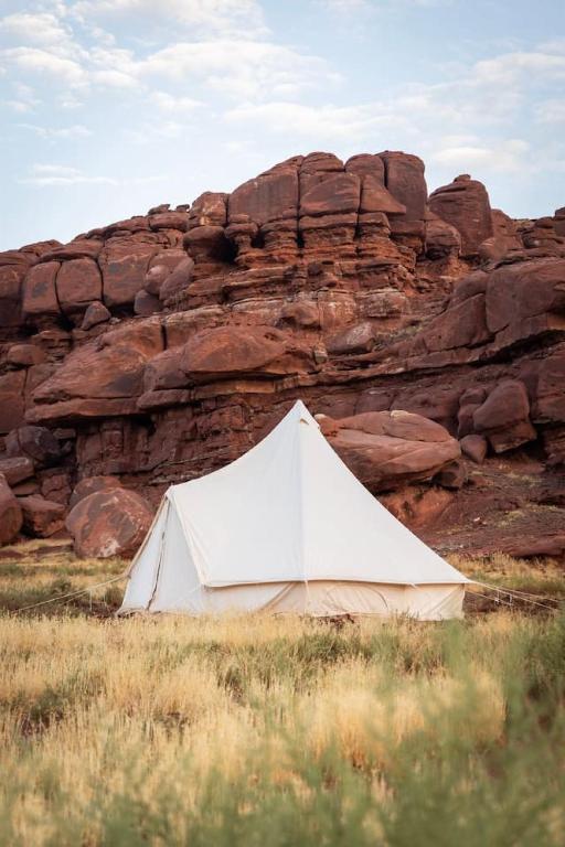 a white tent in front of a rocky mountain at Glamping Queen Tent At Private Riverside Ranch in Moab