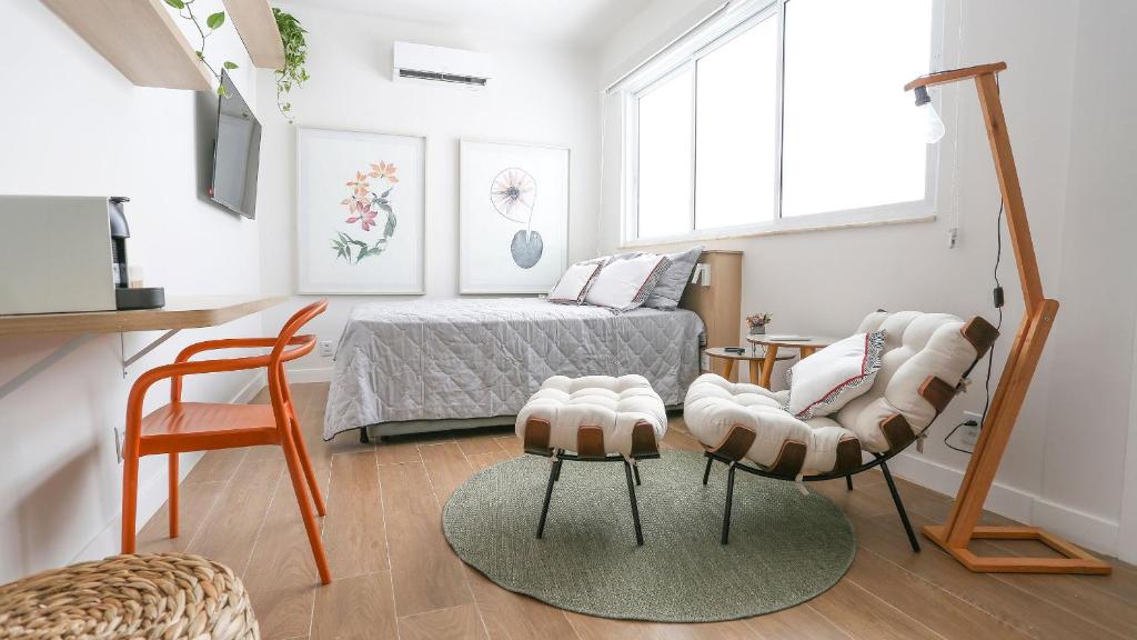 - une chambre avec un lit et deux chaises dans l'établissement Lindo Loft próximo a praia!, à Rio de Janeiro