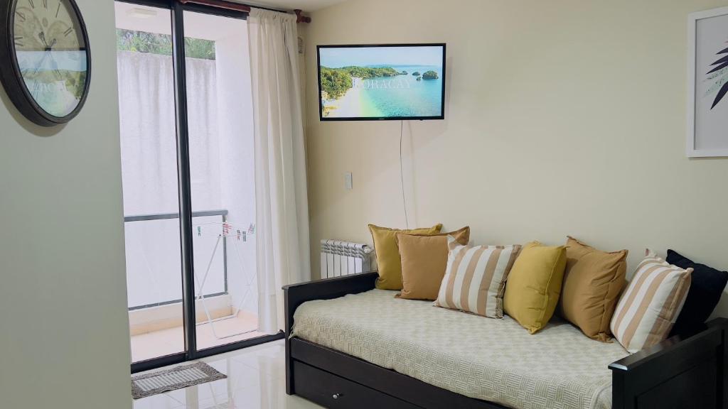a living room with a couch and a clock on the wall at VOW Departamento CÉNTRICO CON COCHERA in Villa Carlos Paz
