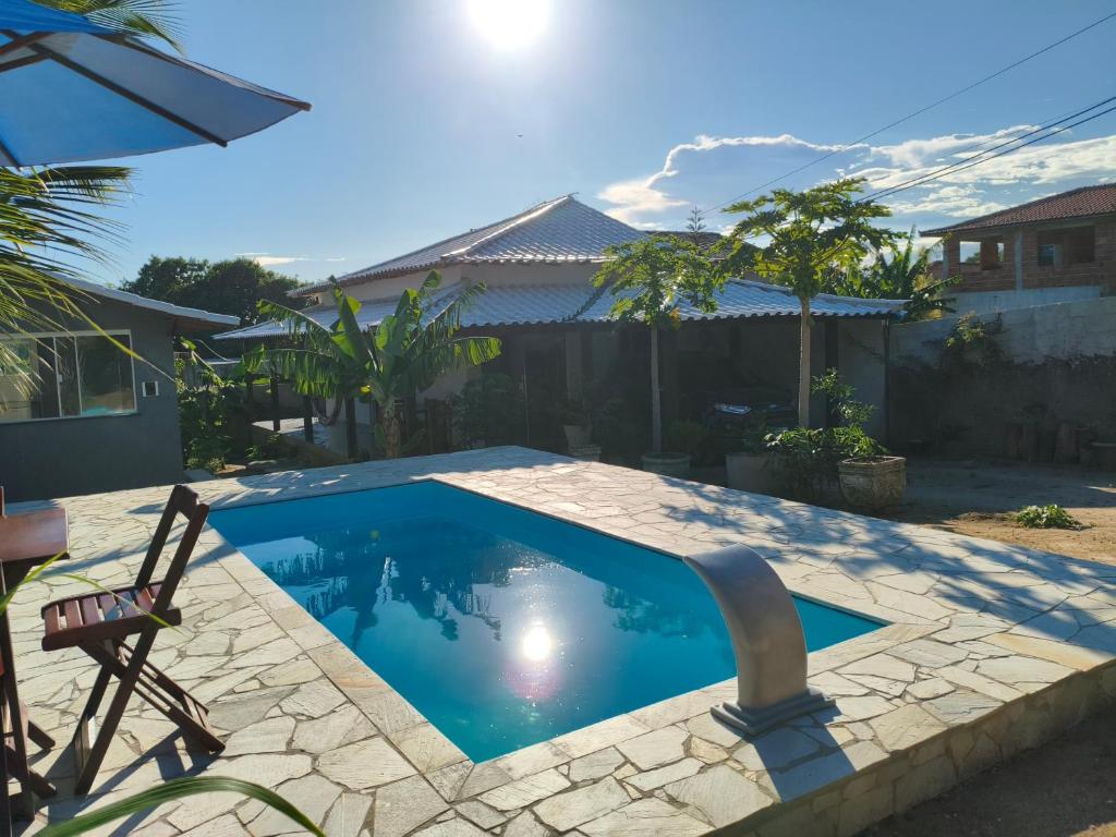 a swimming pool in a yard with a chair next to it at Casa com Piscina em Búzios in Buzios