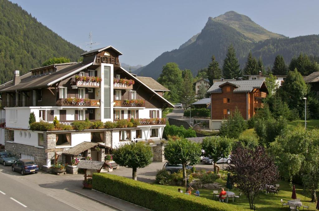 a large building in a town with a mountain at Hôtel Le Sporting in Morzine