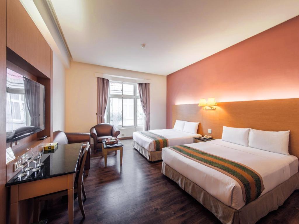 um quarto de hotel com duas camas e uma secretária em Travel Road Motel em Hualien