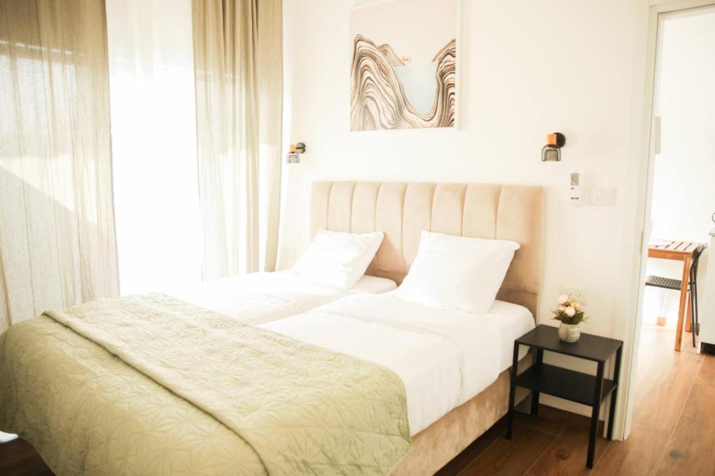 two beds in a hotel room with white walls at נווה מדבר - צימרים ירוחם in Yeroẖam