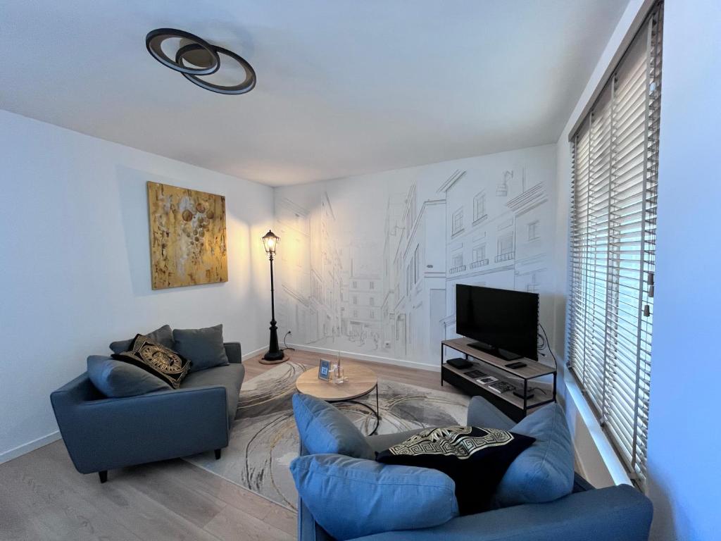 - un salon avec deux canapés bleus et une télévision dans l'établissement La Bulle Dorée, à Épernay