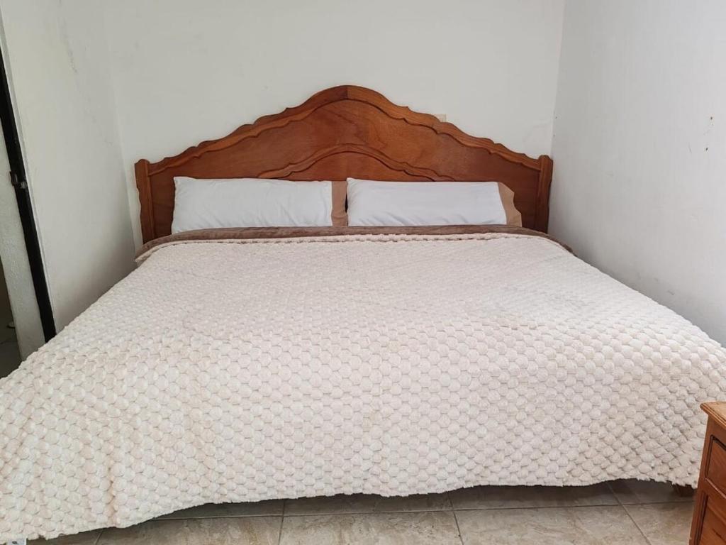ein Bett mit einem hölzernen Kopfteil in einem Schlafzimmer in der Unterkunft Beautiful apartment near the Guadalupe walkway in San Cristóbal de las Casas