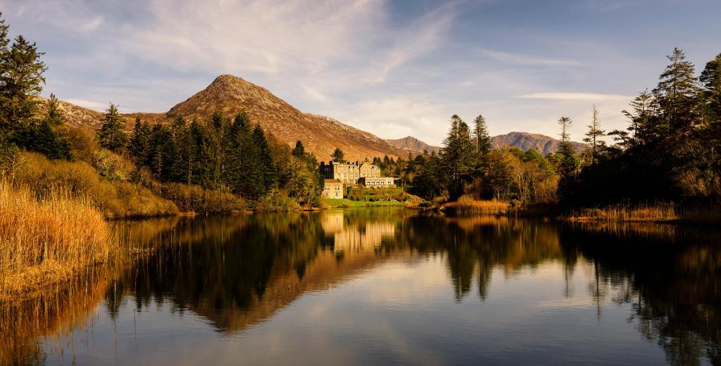 una casa su un lago di fronte a una montagna di Ballynahinch Castle Hotel a Ballynahinch