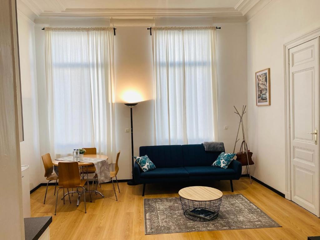 a living room with a blue couch and a table at Studio calme et lumineux à Uccle in Brussels
