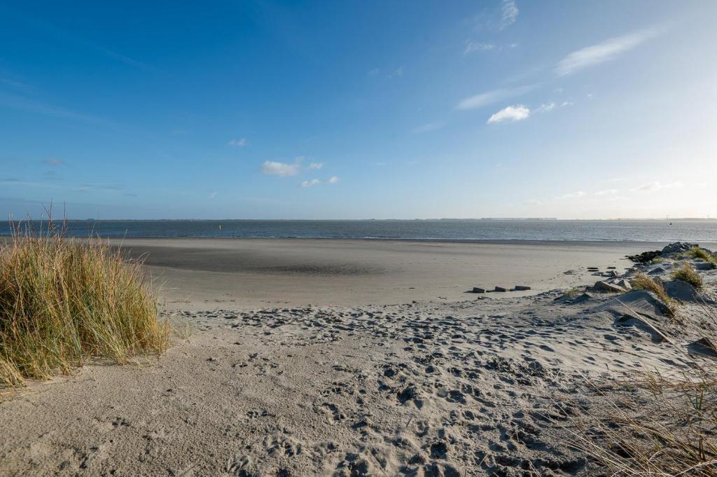 a sandy beach with the ocean in the background at De Strandloper Vakantiehuisje aan het strand - Ferienwohnung am Meer in Baarland