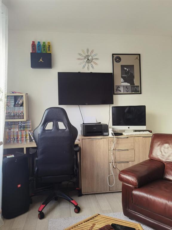 Cette chambre dispose d'une chaise et d'un bureau avec une télévision. dans l'établissement Maison du bonheur, à Dunkerque