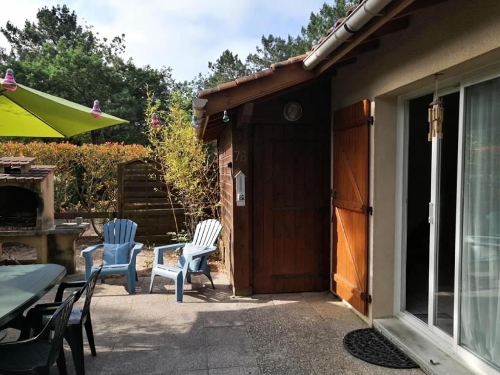 un patio avec des chaises et une table et un bâtiment dans l'établissement Résidence Cigalines - Maisonnette mitoyenne 4 pers, résidence avec piscine, à Lacanau Océan MAE-0371, à Lacanau