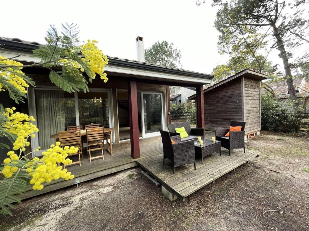 une maison dotée d'une terrasse avec des chaises et une table dans l'établissement Résidence Vitanova - Maison spacieuse 8 personnes proche golf et pistes cyclables à Lacanau Océan MAE-0391, à Lacanau