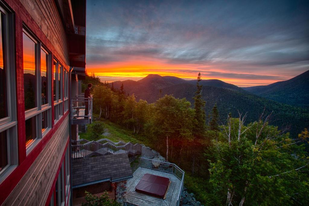 uma vista para o pôr-do-sol a partir de uma varanda de uma casa em Auberge de Montagne des Chic-Chocs Mountain Lodge - Sepaq em Sainte-Anne-des-Monts