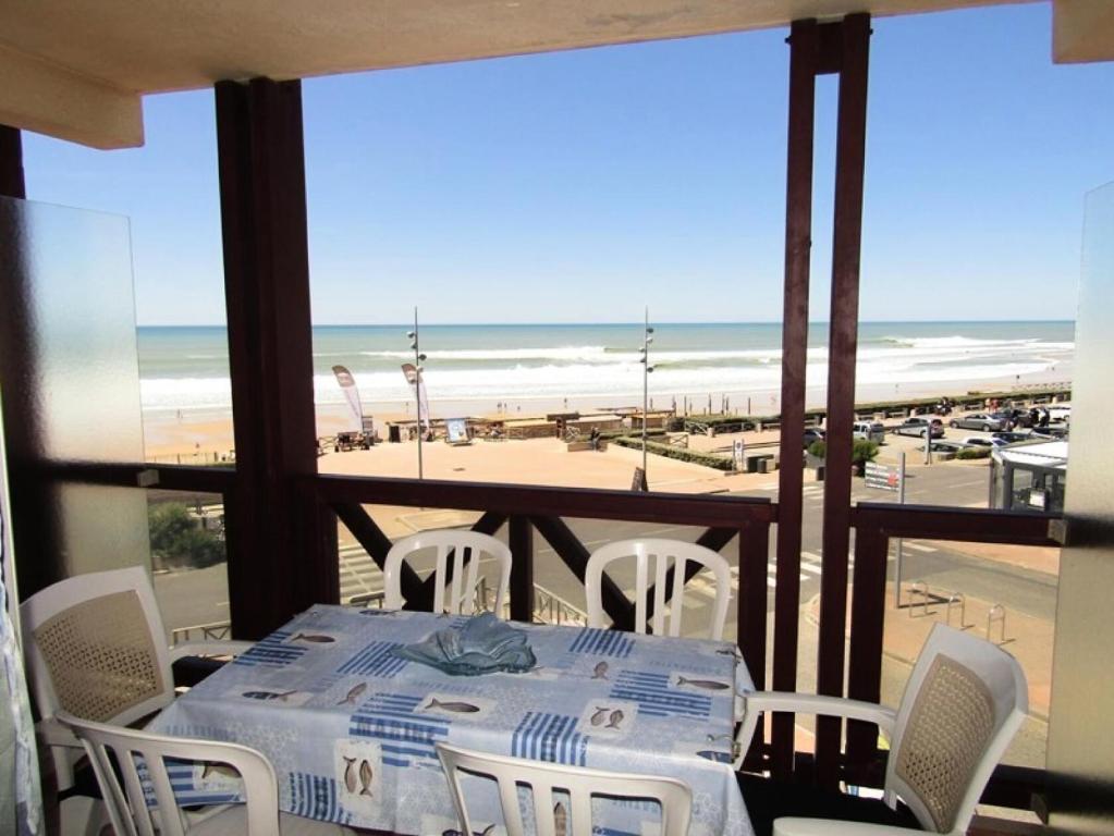 - une table avec des chaises blanches et une vue sur la plage dans l'établissement Résidence Les Cytises - Appartement vue mer pour 4 personnes à Lacanau Océan MAE-0671, à Lacanau