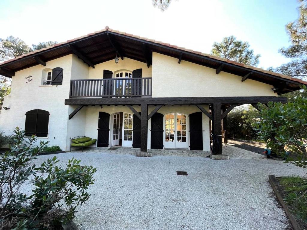 Cette grande maison blanche dispose d'un balcon. dans l'établissement Résidence 05029-lacanau Ocean - Villa pour 9 personnes avec jardin et jacuzzi à Lacanau Océan MAE-1001, à Lacanau