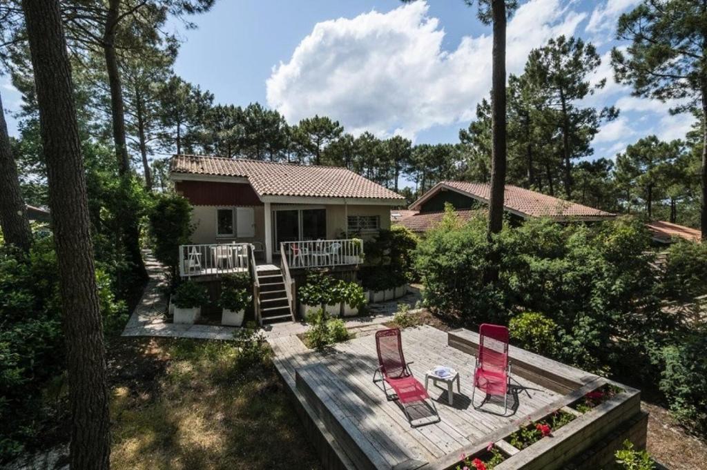 une maison avec deux chaises sur une terrasse en bois dans l'établissement Résidence Golf Loisirs - Maison classée 1 pour 6 personnes, résidence avec piscine, Lacanau Océan MAE-1111, à Lacanau