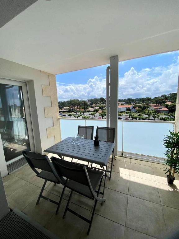 une salle à manger avec une table et des chaises sur un balcon dans l'établissement Résidence Les Embruns - Appartement neuf à proximité des commodités pour 4 personnes avec parking MAE-9381, à Lacanau