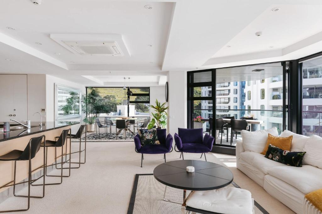a living room with a couch and a table at Spectacular Sunrises & Sea Views - Pool Spa Gym in Mount Maunganui