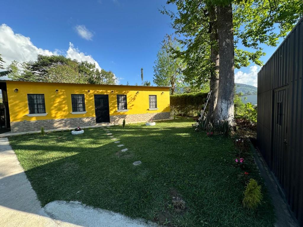a yellow house with a tree in the yard at Casa de Campo in Santa Cruz Verapaz