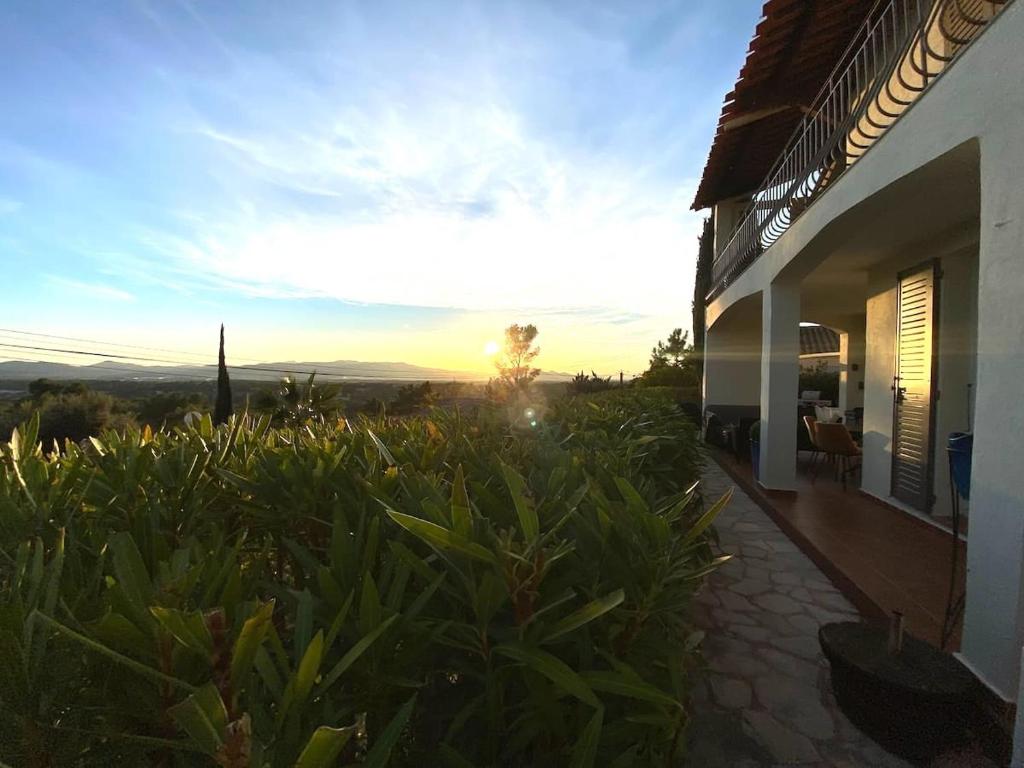 - une vue sur une maison avec le coucher du soleil en arrière-plan dans l'établissement Maison au calme dans résidence privée avec piscine vue mer, à Fréjus