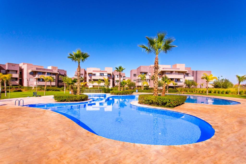 een zwembad van het resort met palmbomen en gebouwen bij Privilege house Opale in Marrakesh