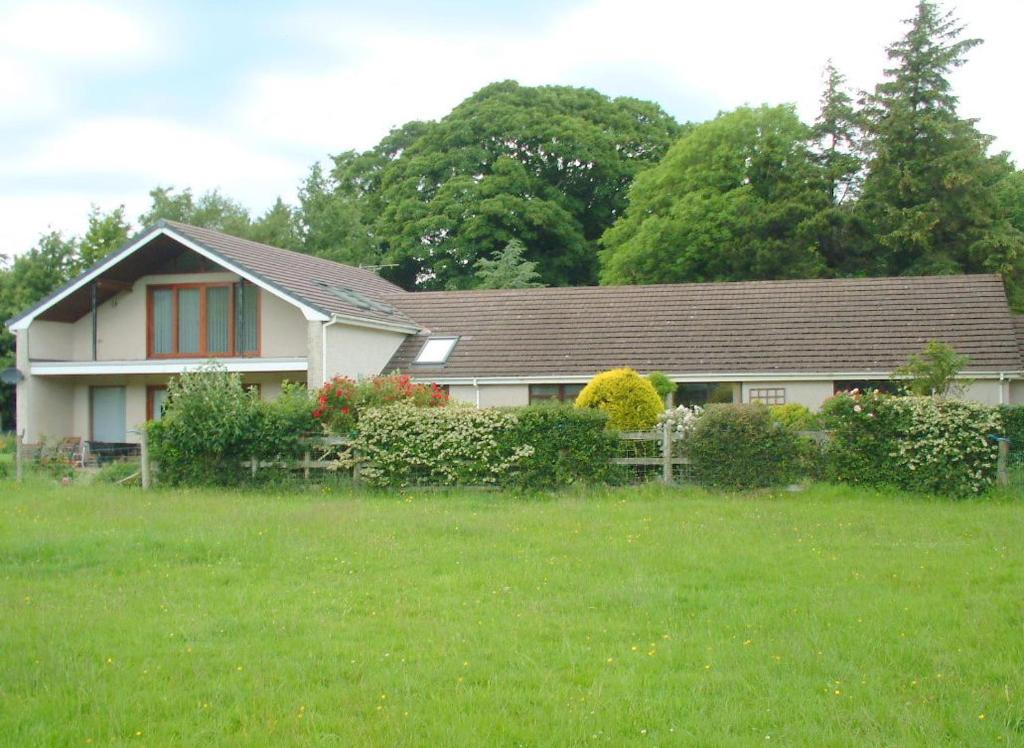 uma casa branca com janelas vermelhas e um quintal em Ballacowell em Sulby