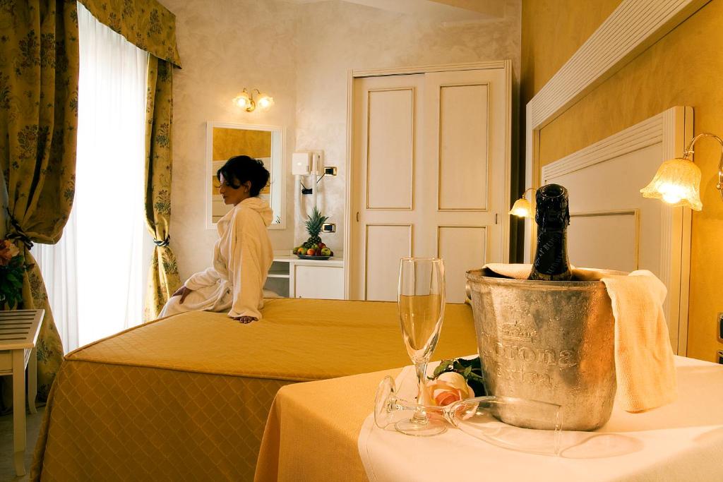 a woman sitting on a bed in a hotel room at Hotel Diplomat Palace in Rimini