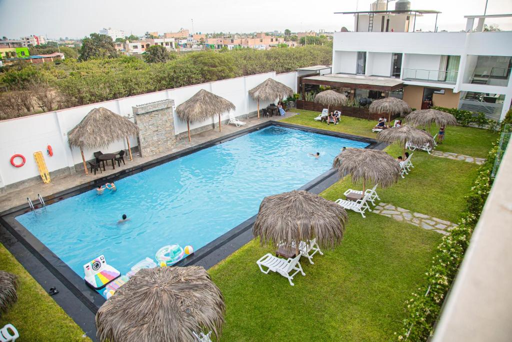 an overhead view of a swimming pool with chairs and umbrellas at Hotel Kendari - Chincha in Chincha