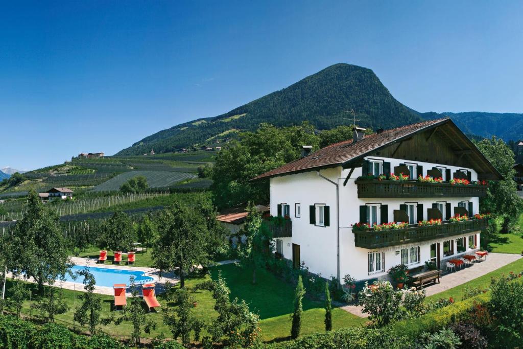 Una gran casa blanca con piscina y montañas en el fondo en Garni Pluner, en Scena