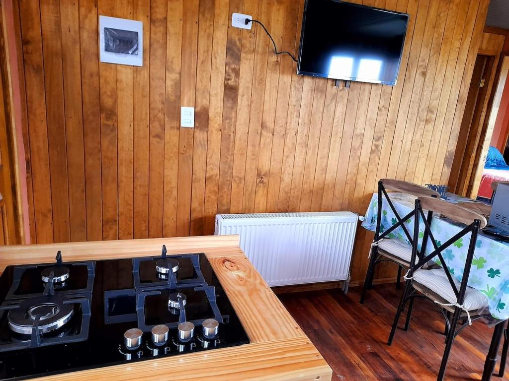 cocina con fogones y TV en una habitación en Cabaña Aquiles, en Puerto Natales