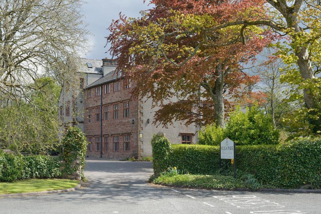 a street in front of a building with trees and bushes at Sella Park Country House Hotel in Seascale