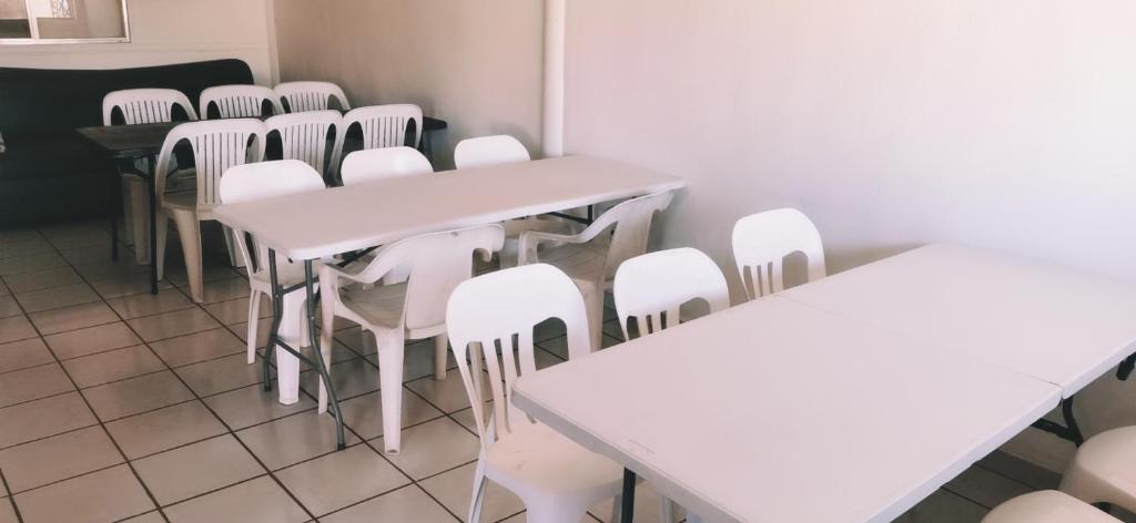 a room with white tables and white chairs at Salón y habitaciones in San Patricio