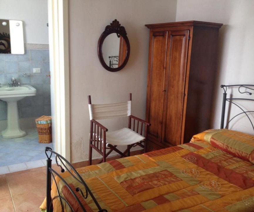 a bedroom with a bed and a chair and a mirror at B&B Le Due Corti in Martignano